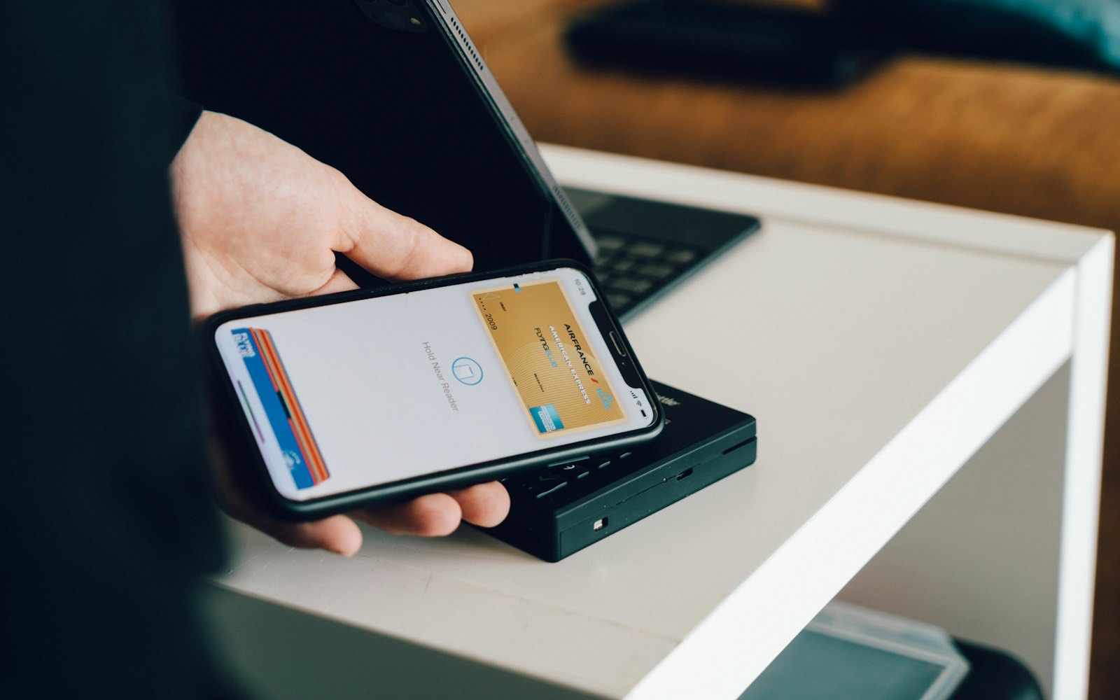 A phone held to a card reader at a counter